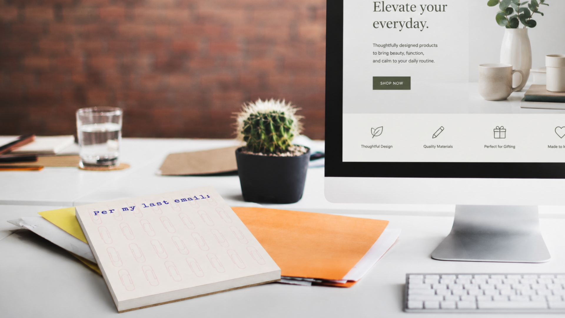 Modern office desk with computer, notebook, and cactus on a blurred background